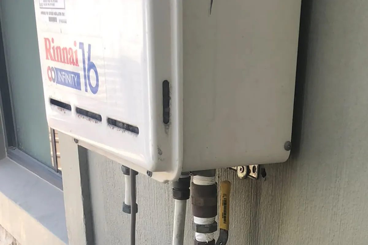 Rinnai Infinity gas geyser wall mounted in open air on the outside of a Cape Town house, with the gas line and water connections below it